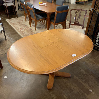 Wooden dining table with a single extension leaf in an indoor setting
