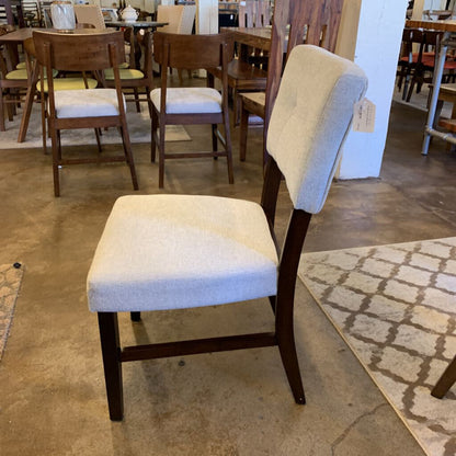 Dining room chairs with wooden frames and upholstered seats in a showroom setting.