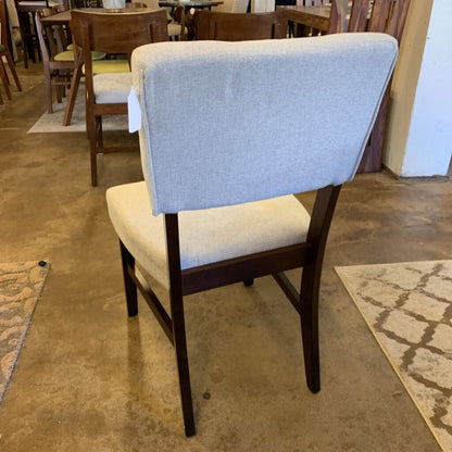 Chair with gray backrest and beige seat in a room with tables and chairs.