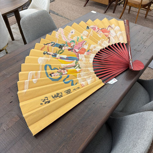 Decorative fan with colorful design on a wooden table