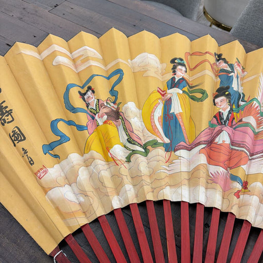 Traditional Chinese fan with colorful illustrations of people on a yellow background