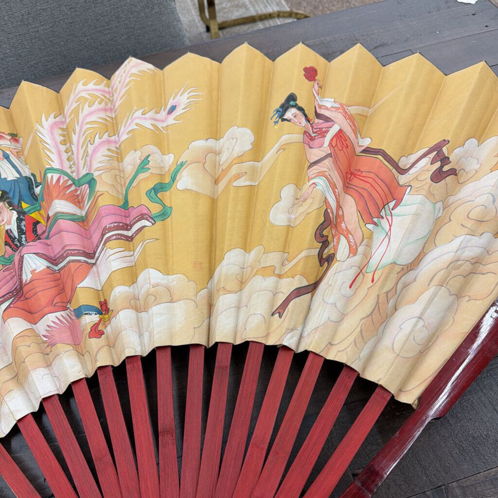 Traditional Chinese fan with colorful illustrations on a wooden surface