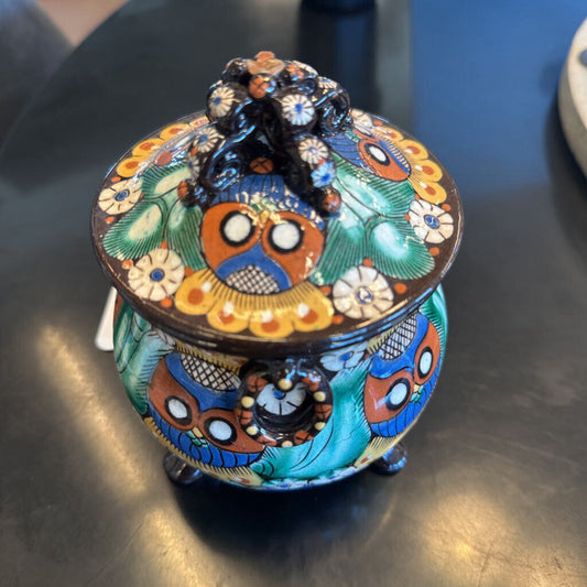 Decorative ceramic jar with intricate designs on a metallic surface