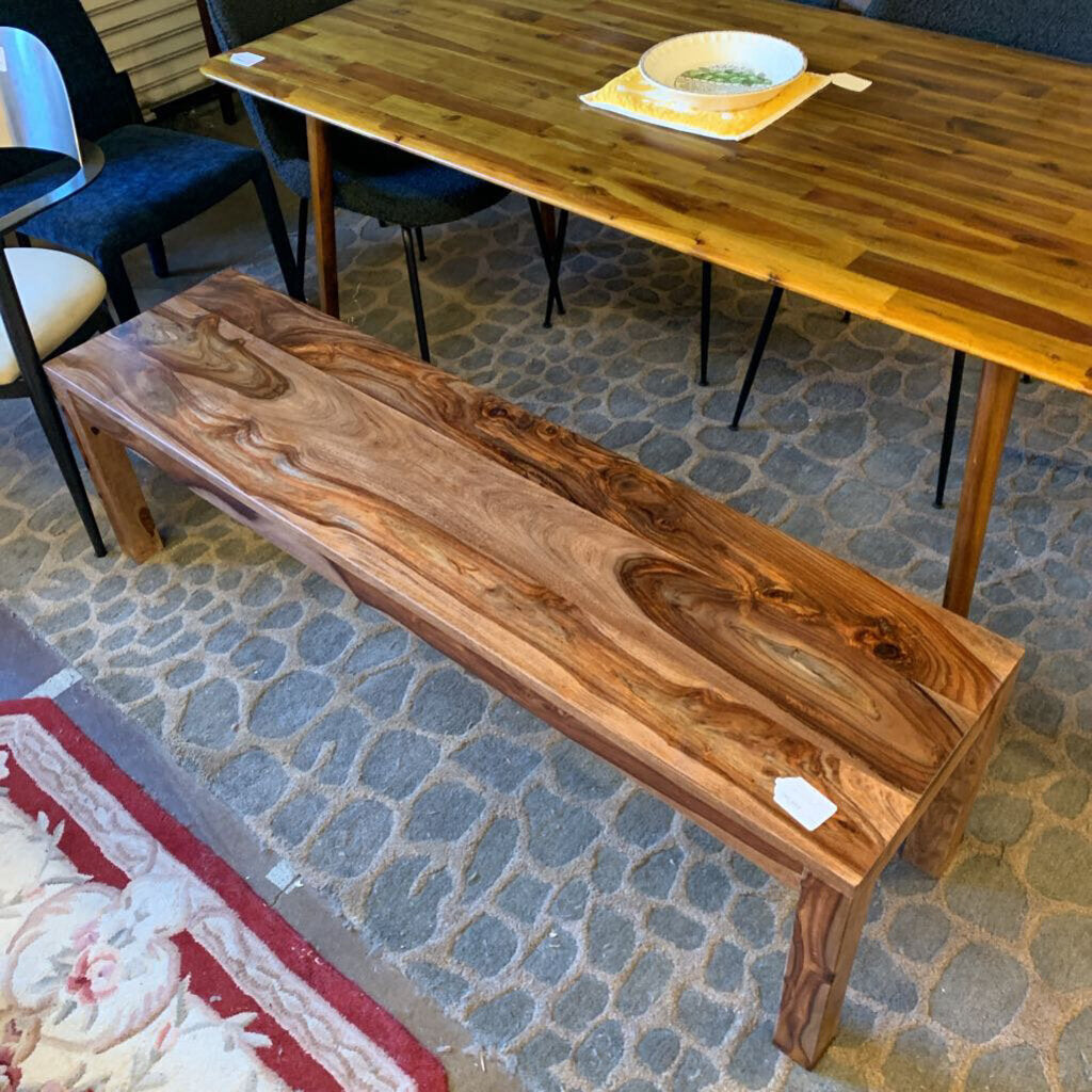 Wooden bench and table on a stone floor with chairs in the background