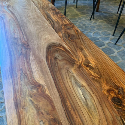 Wooden table with a unique grain pattern on a stone floor.