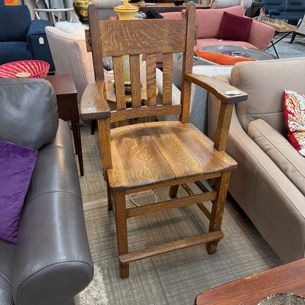 Wooden chair in a room with furniture including a gray sofa and a pink couch.