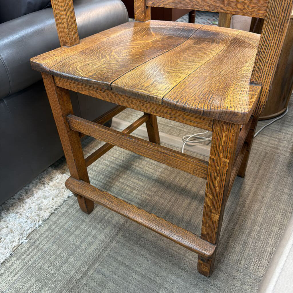 Wooden chair with a worn surface on a carpeted floor.