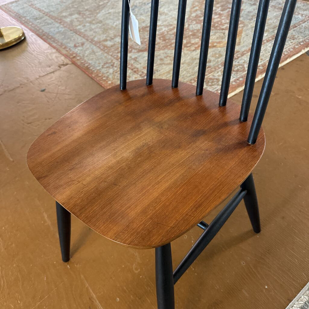 Wooden chair with black metal legs on a brown floor.