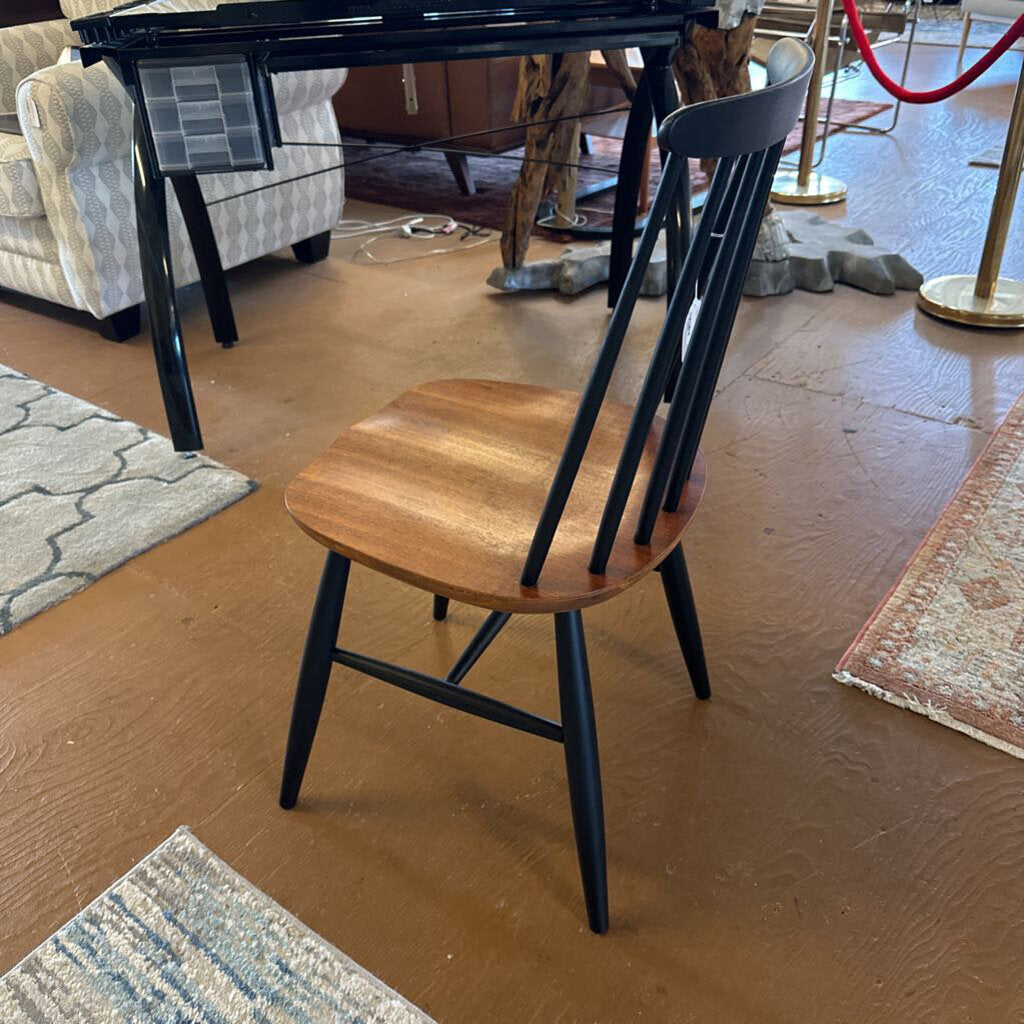 Wooden chair with black legs on a wooden floor in a showroom setting