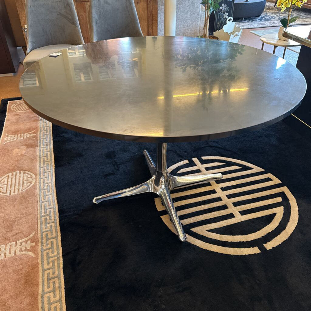 Round metal table with a black base on a patterned rug