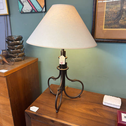 Table lamp with a white shade on a wooden surface against a green wall.
