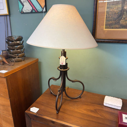 Table lamp with a white shade on a wooden surface against a green wall.