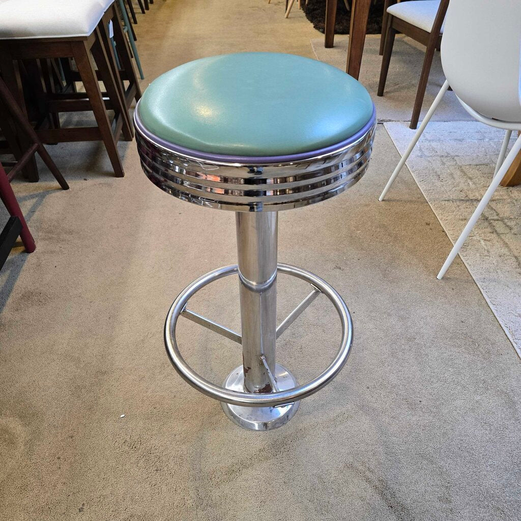 Bar stool with green cushioned seat and metal base in a room setting