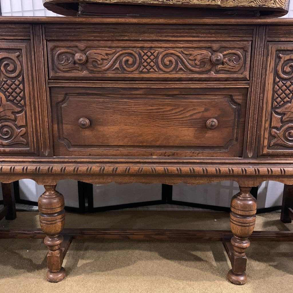 Wooden sideboard with intricate carvings and a drawer.