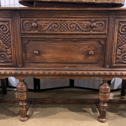 Wooden sideboard with intricate carvings and a drawer.