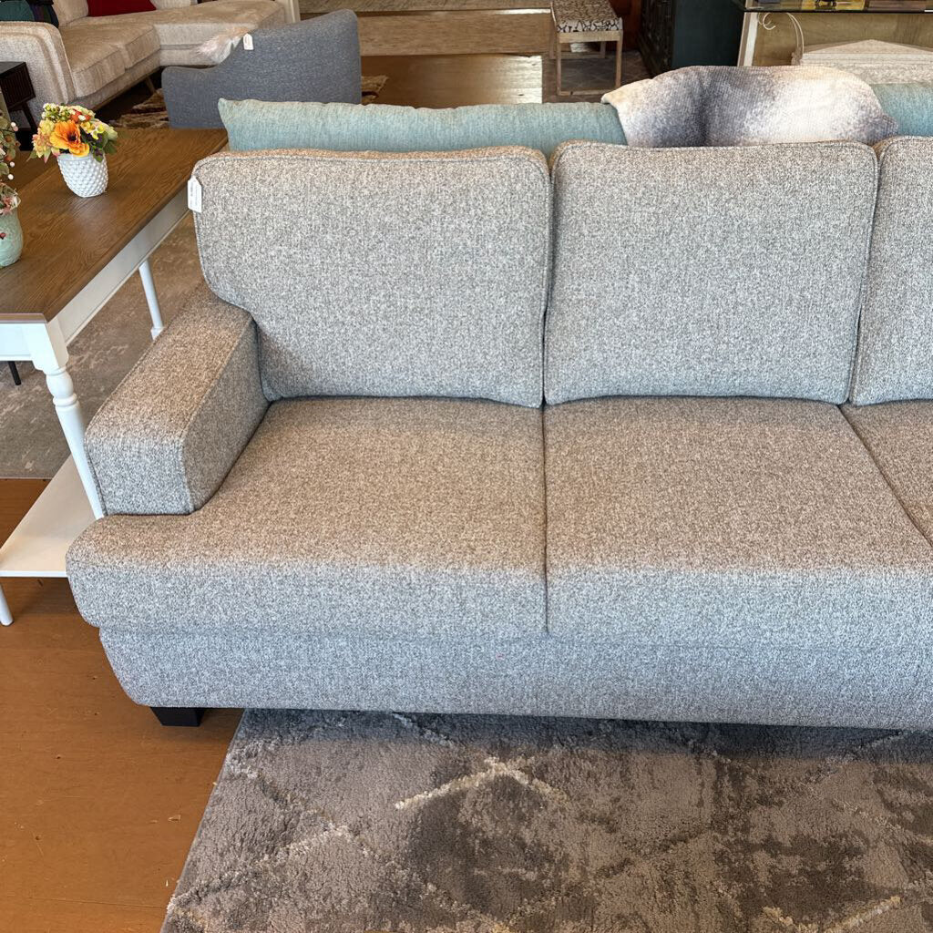 Gray sofa in a living room setting with a coffee table and rug.