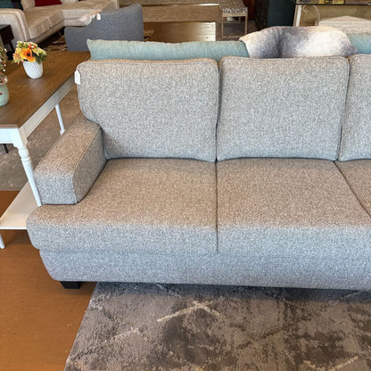 Gray sofa in a living room setting with a coffee table and rug.
