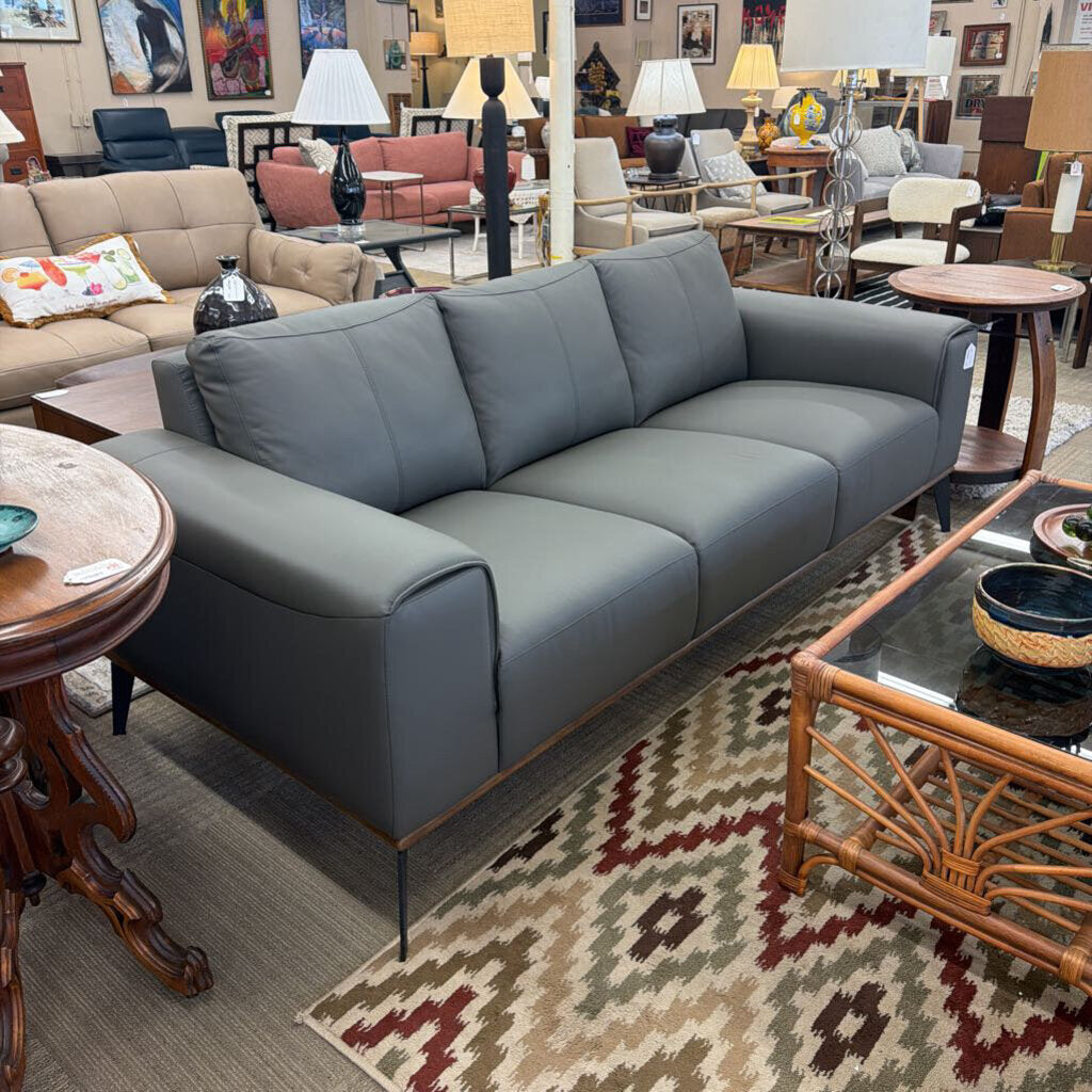 Gray sofa in a room with various furniture and decor items.