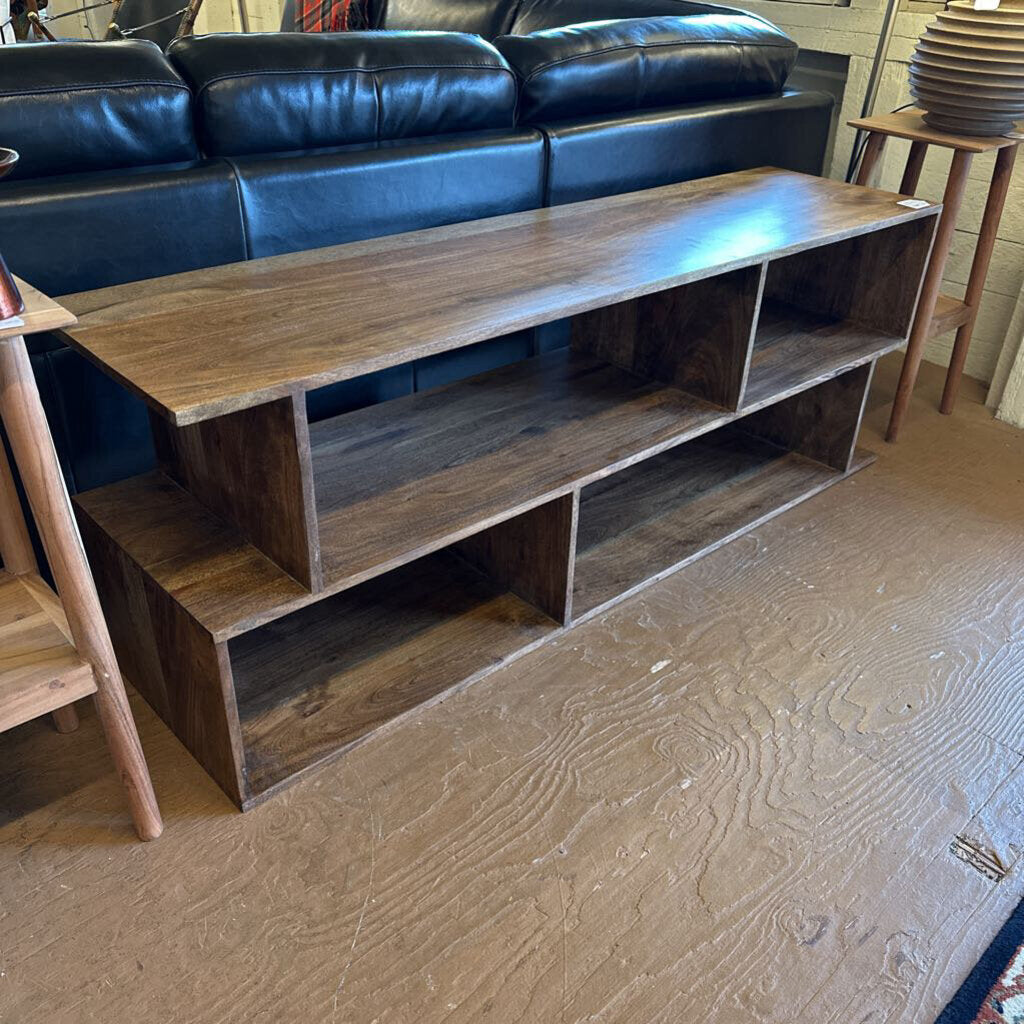 Wooden entertainment console in a living room setting with a blue sofa.