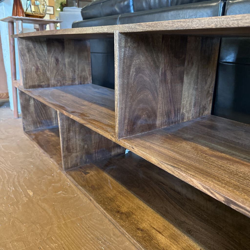 Wooden shelf unit with a black sofa in the background