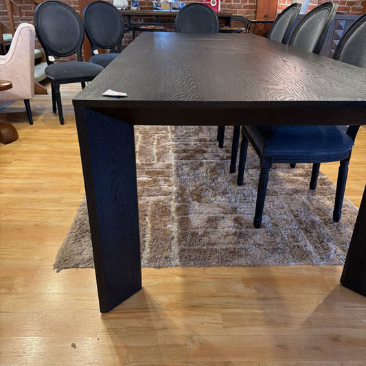 Dining table with chairs in a room with wooden floor and brick wall.