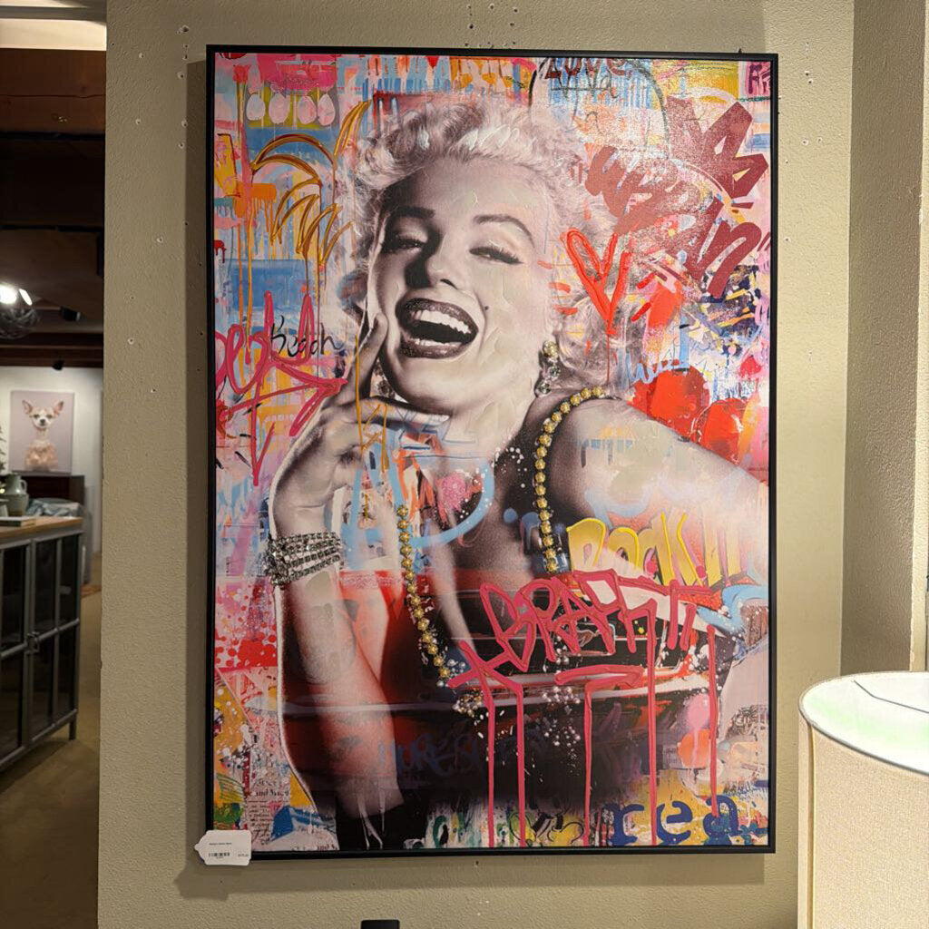 Framed artwork of a stylized portrait with colorful abstract elements on a wall.