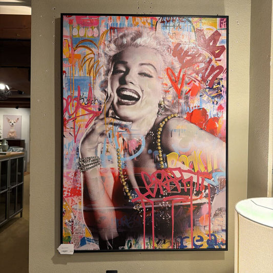 Framed artwork of a stylized portrait with colorful abstract elements on a wall.