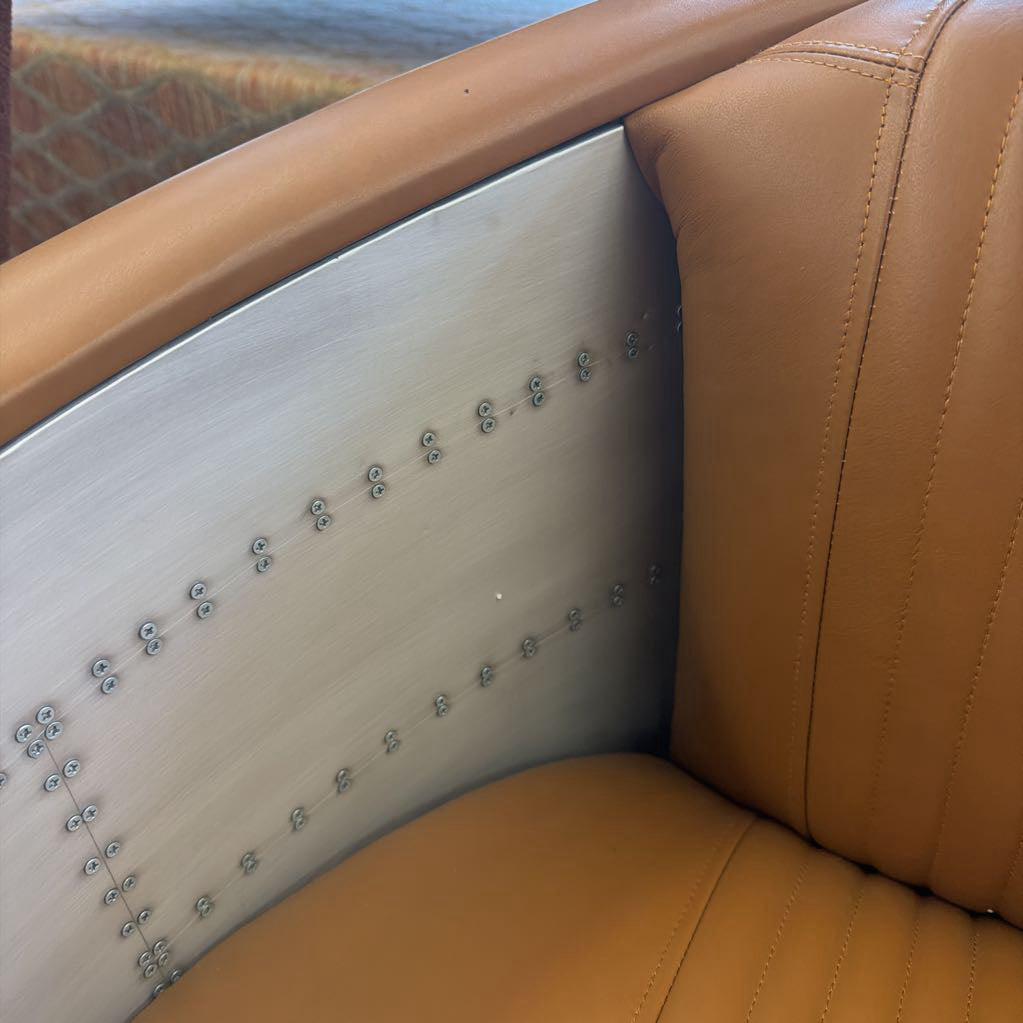 Close-up of a brown leather car seat with decorative studs.