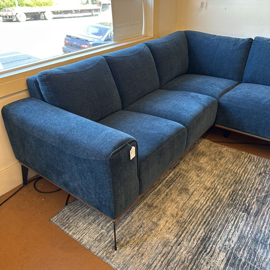 Blue sectional sofa in a room with a window and wooden floor.