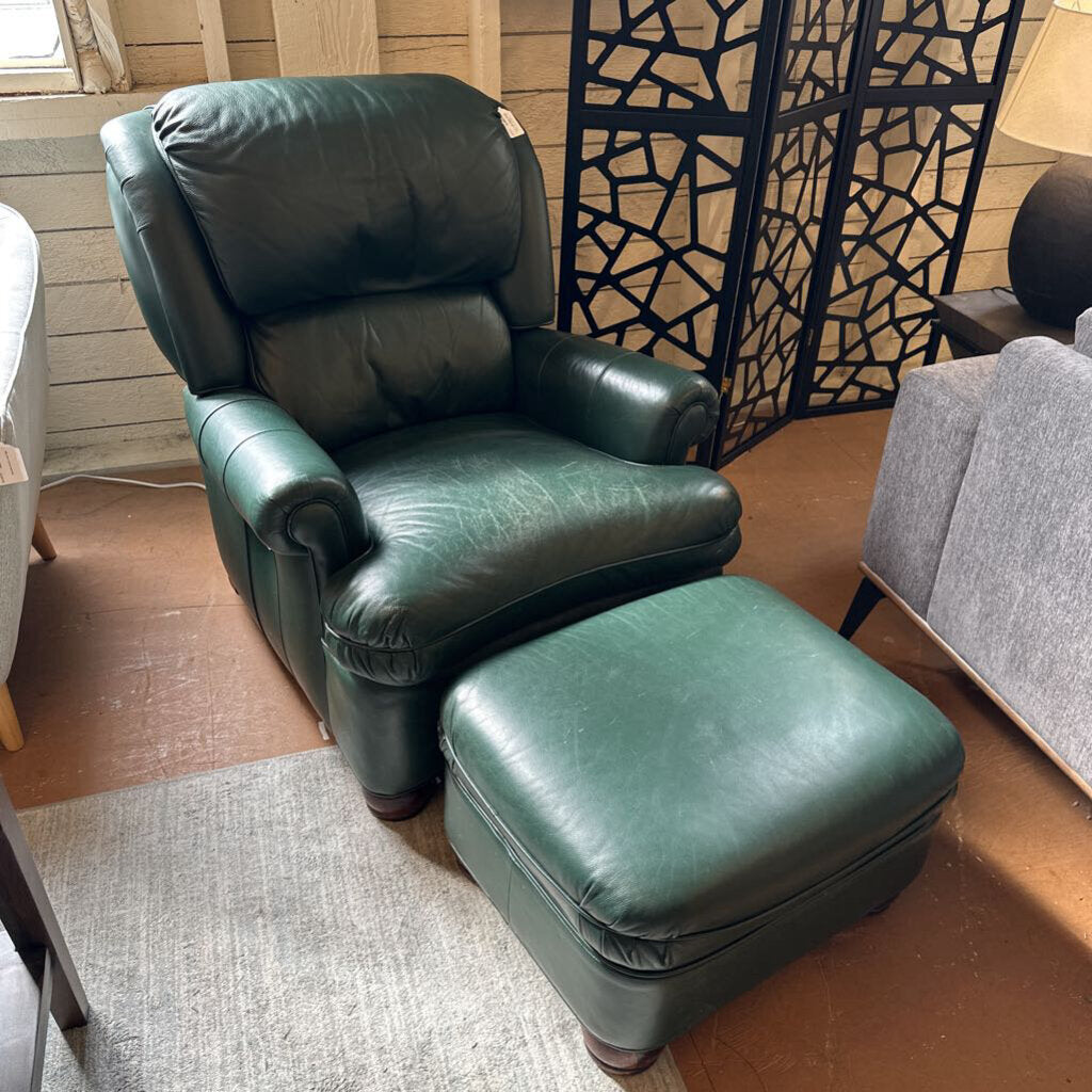 Green leather armchair with ottoman in a room with wooden floor and decorative screen.