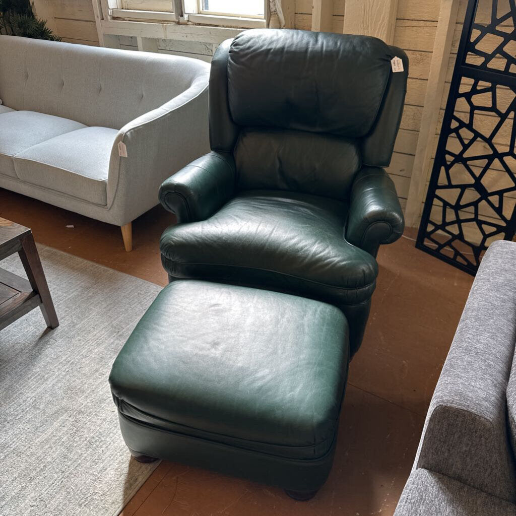 Green leather armchair and ottoman in a living room setting with a gray sofa and decorative screen.