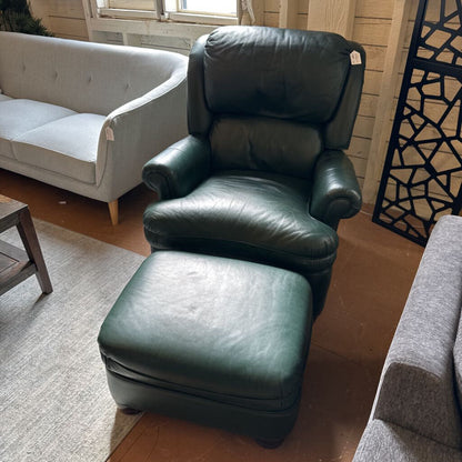 Green leather armchair and ottoman in a living room setting with a gray sofa and decorative screen.