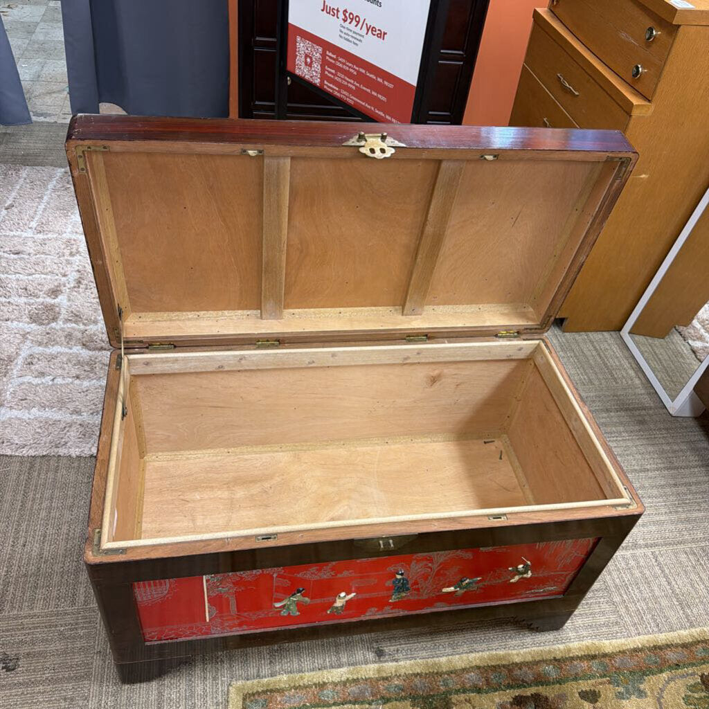 Wooden trunk with red decorative panel on a carpeted floor