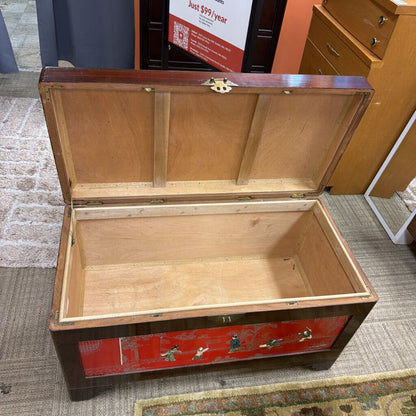 Wooden trunk with red decorative panel on a carpeted floor