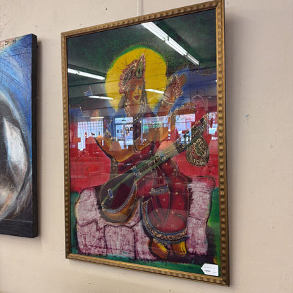 Framed artwork of a deity playing a stringed instrument on a beige wall.