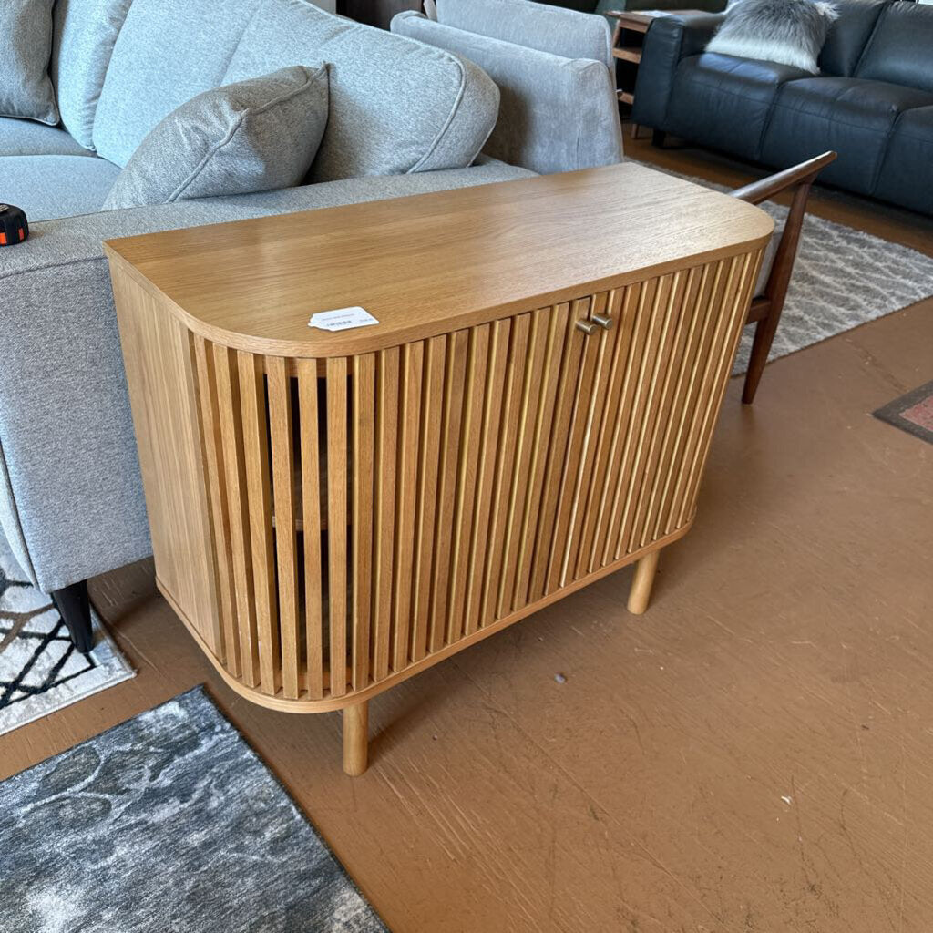 Wooden sideboard in a living room setting with gray sofa and rug.