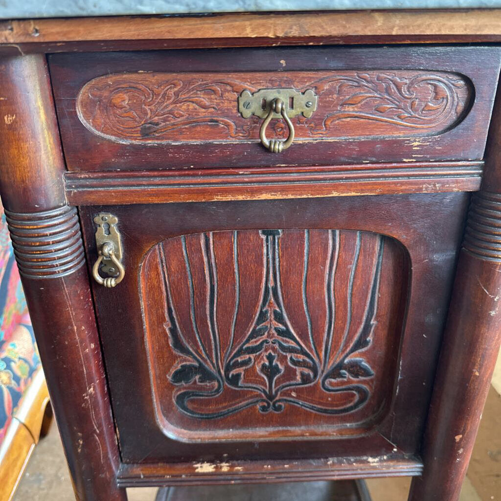 Close-up of an ornate wooden desk with intricate carvings and brass handles.