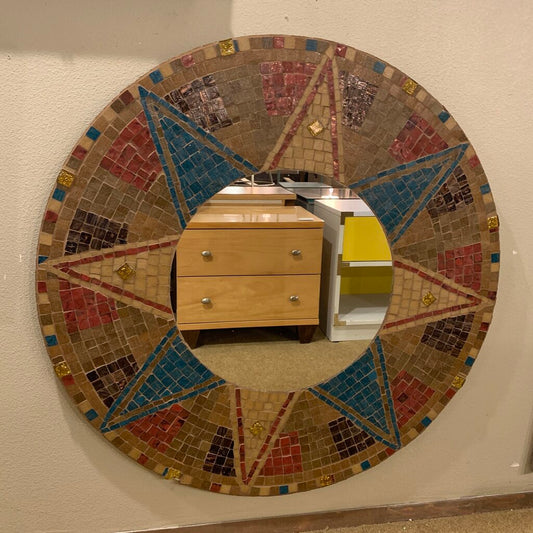 Round mosaic mirror with geometric design on a wall