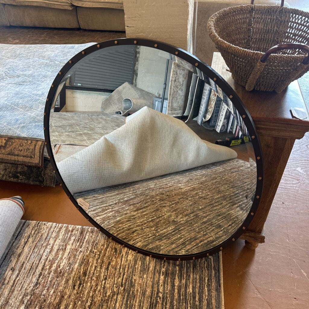 Round mirror reflecting a room with a table and chair.