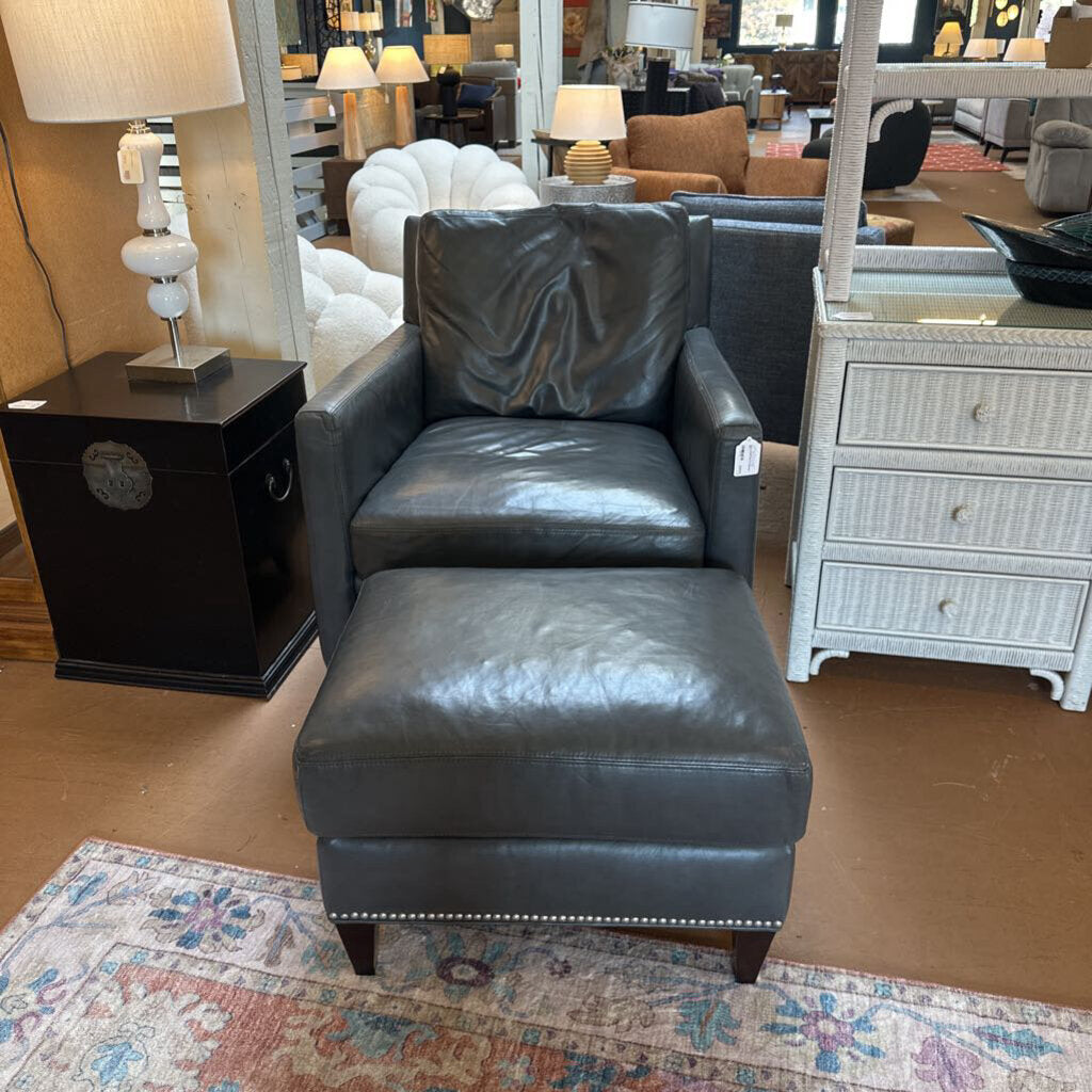Gray leather armchair with matching ottoman in a showroom setting