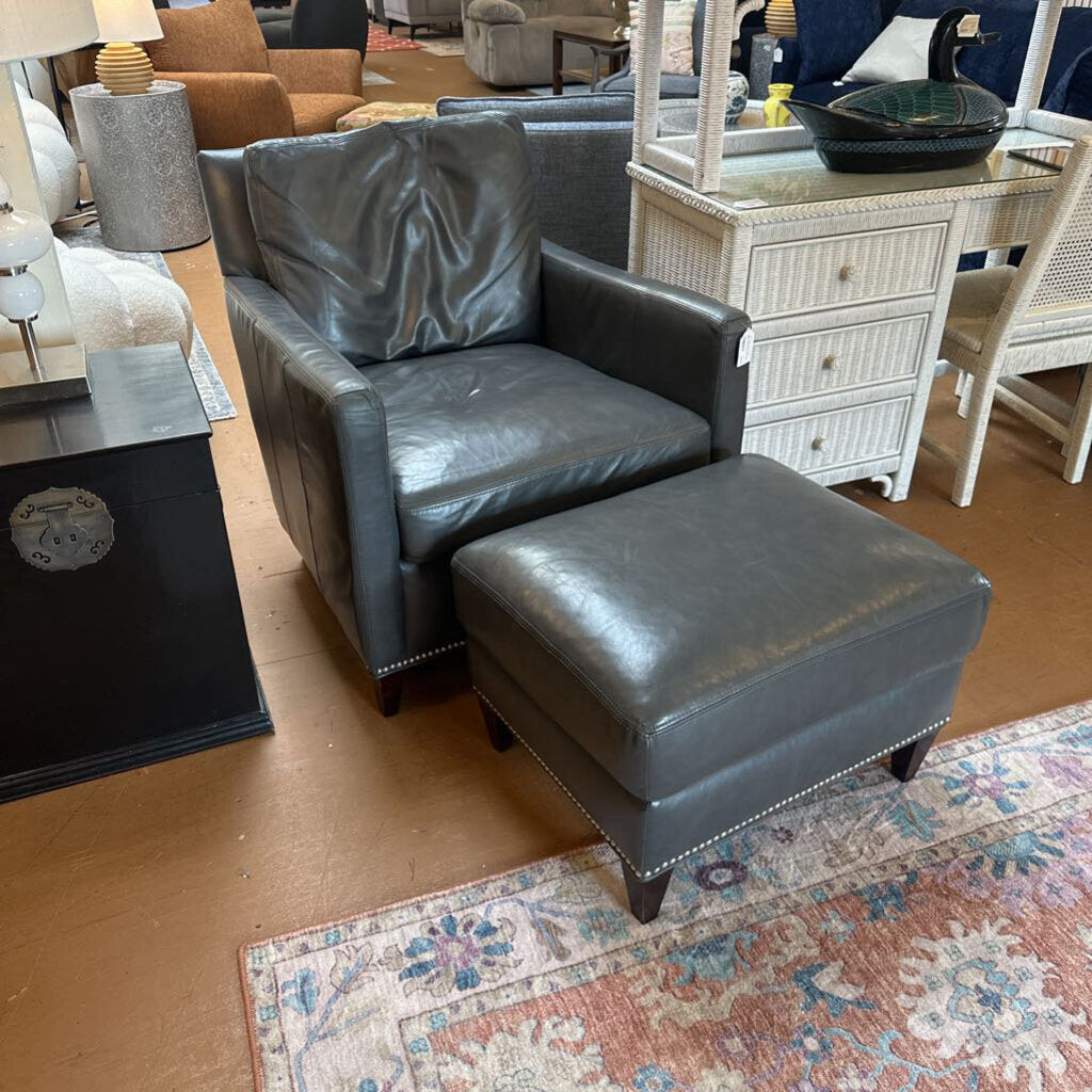 Gray leather armchair and ottoman on a patterned rug with furniture in the background