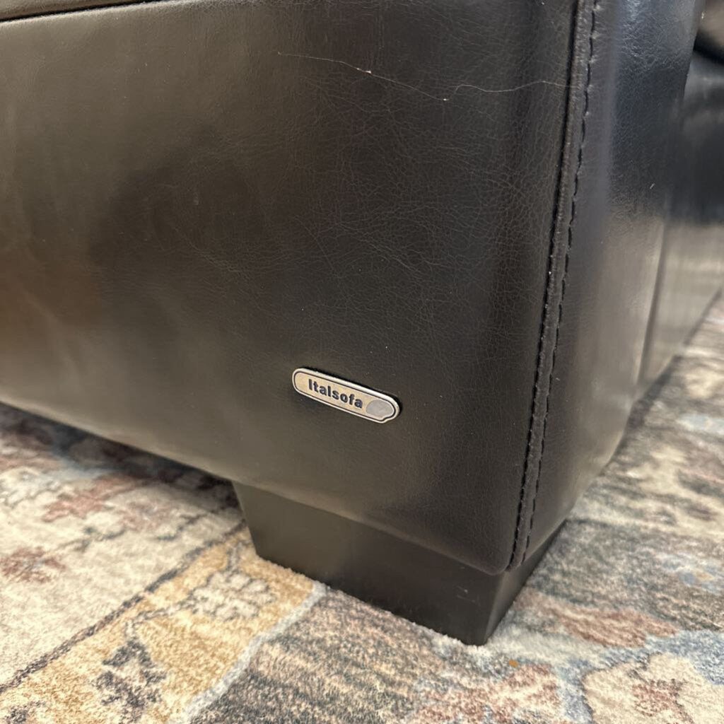 Brown leather bag with 'Italia' brand label on a patterned surface