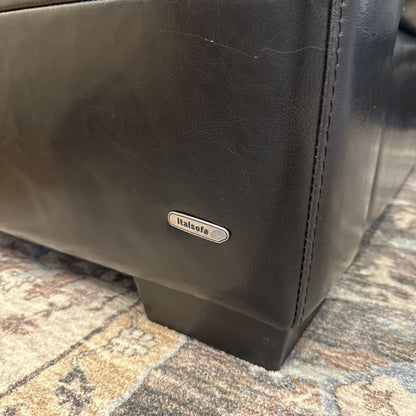Brown leather bag with 'Italia' brand label on a patterned surface