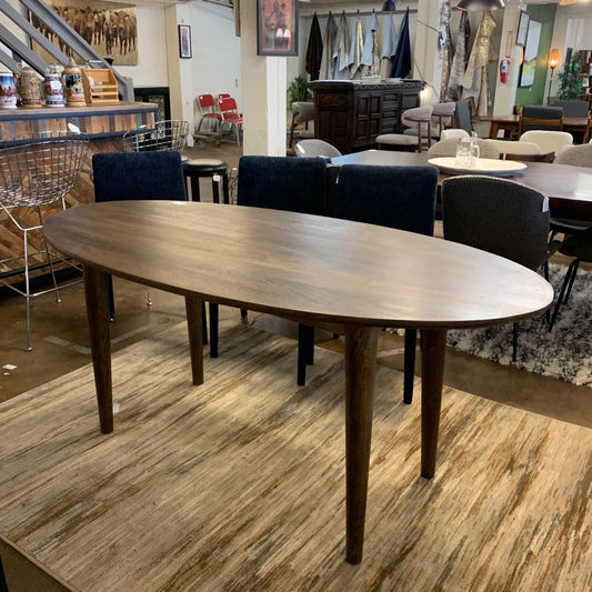 Wooden dining table in a showroom with chairs and decor.