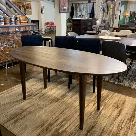 Wooden dining table in a showroom with chairs and decor in the background