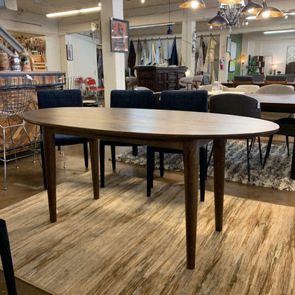 Wooden dining table in a showroom with chairs and decor in the background