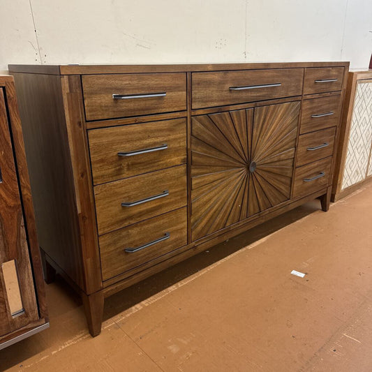Wooden dresser with sunburst design on a brown floor.