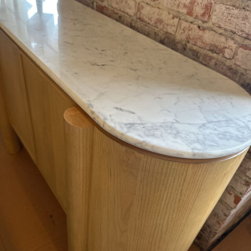 Wooden bench with marble-like top against a brick wall.