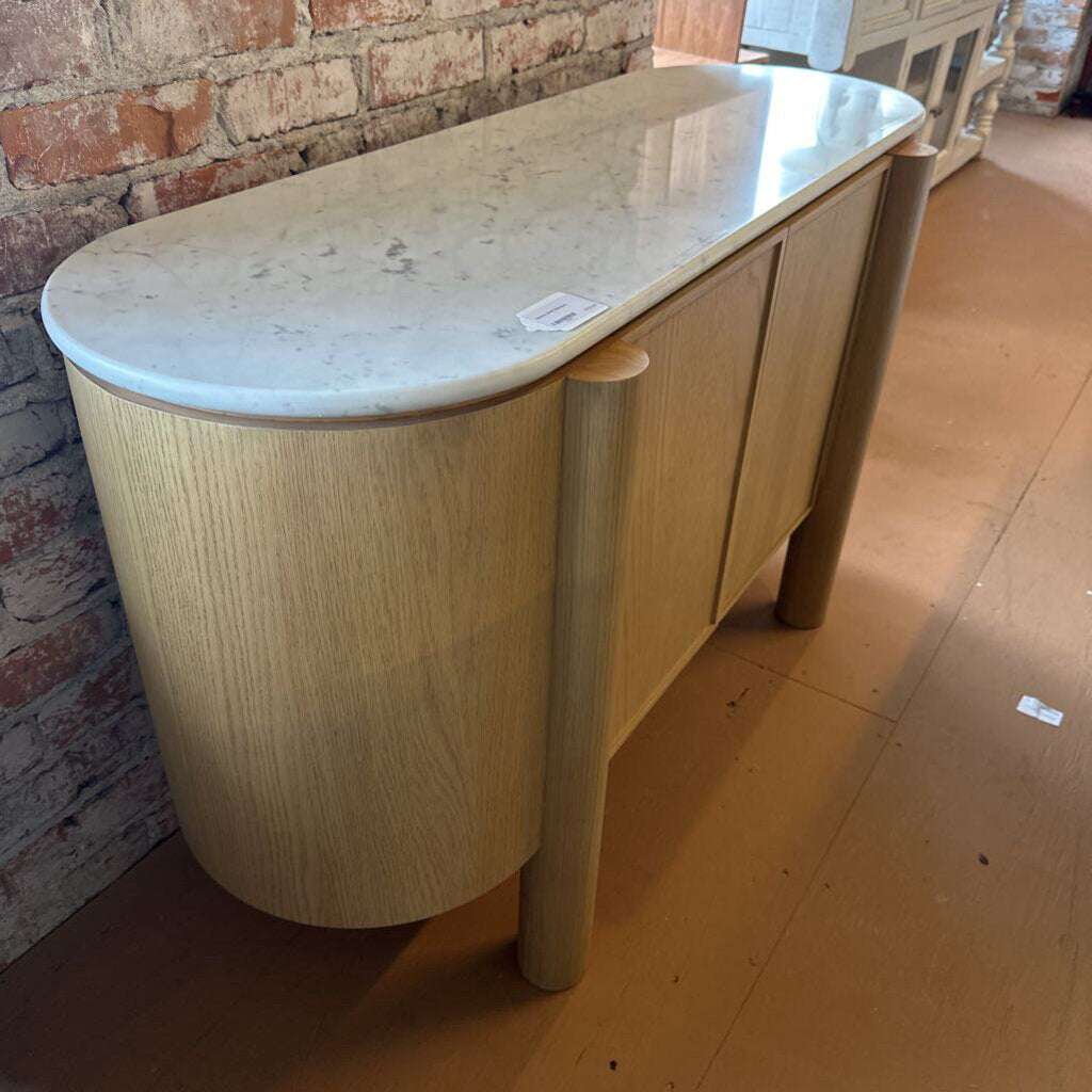 Wooden console table with marble top against a brick wall.