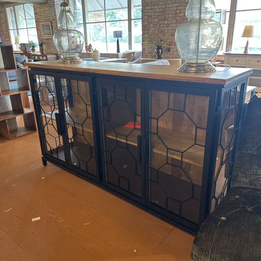 Cabinet with geometric glass panels in a room with large windows and furniture.